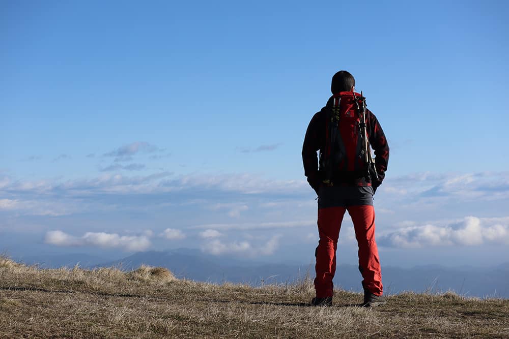 hombre montañero mirando al infinito desde una montaña