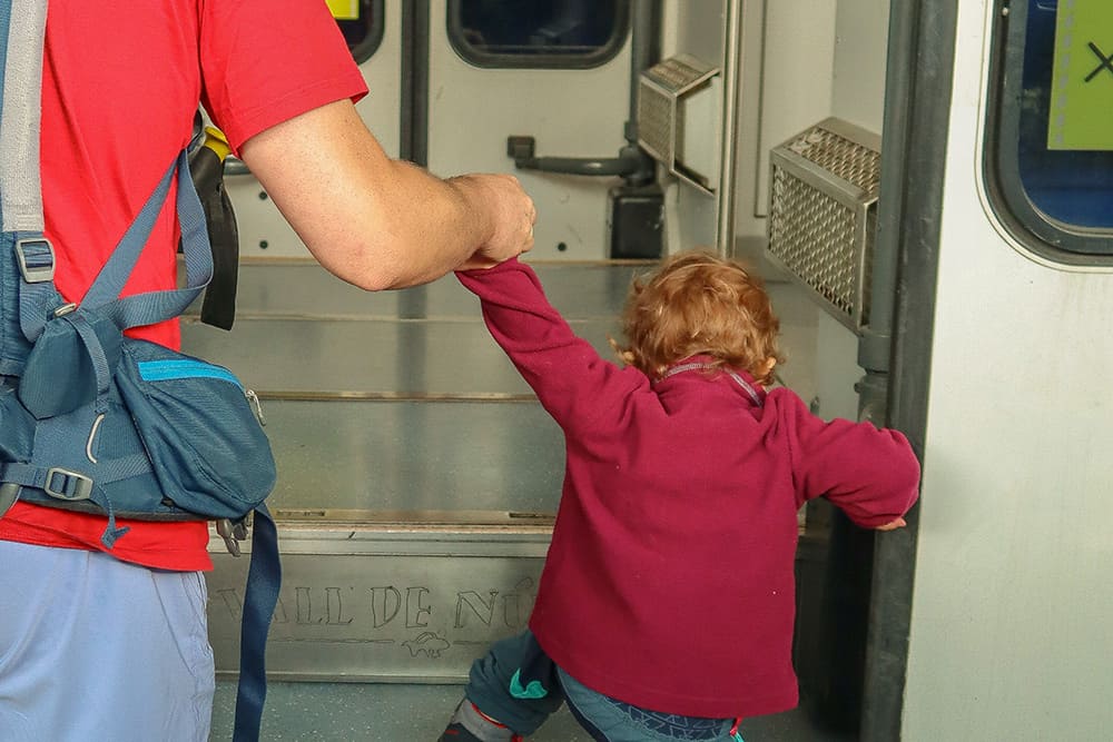 un niño ayudado por su padre subiendo a un tren
